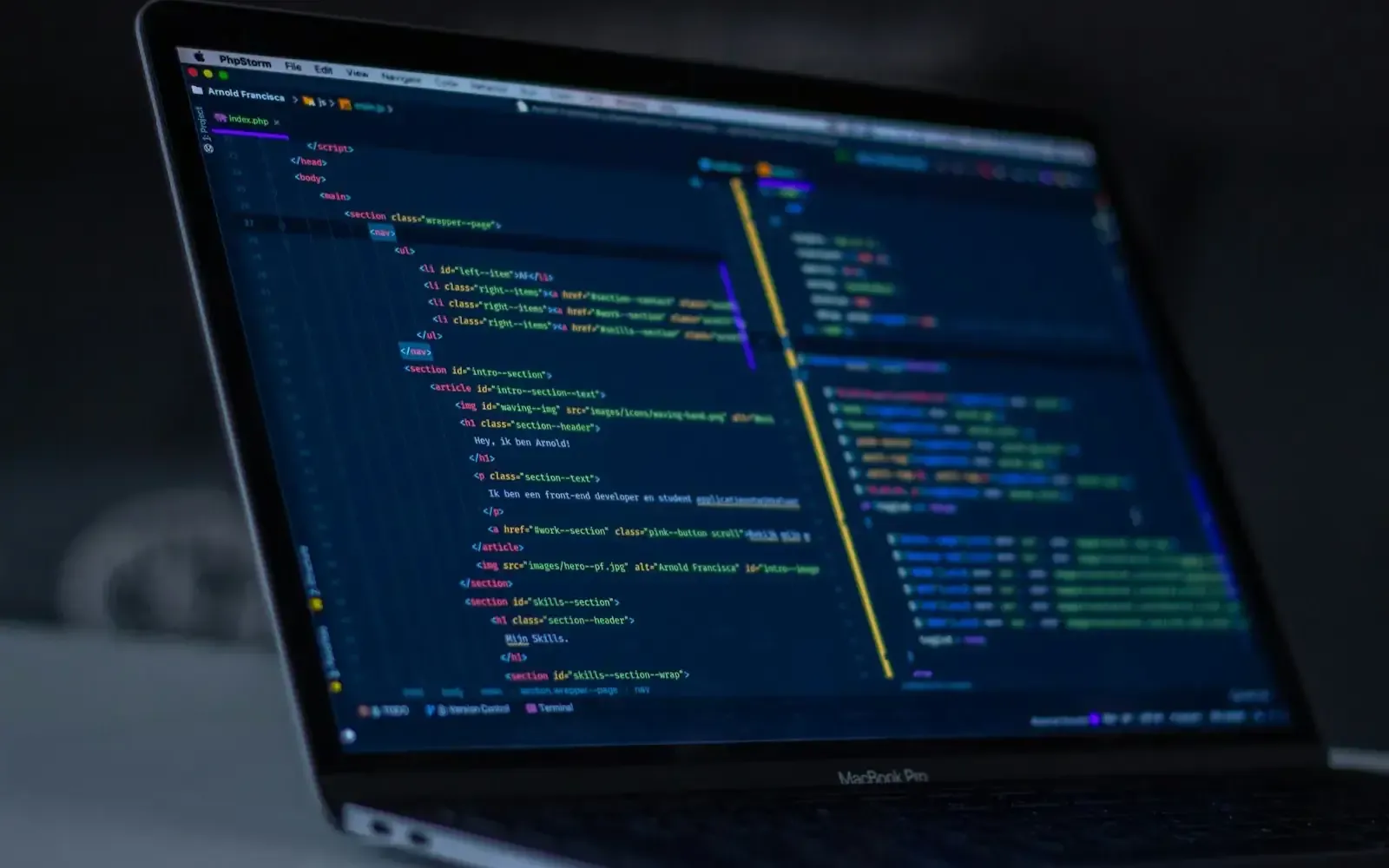 A laptop showing source code in a dark room